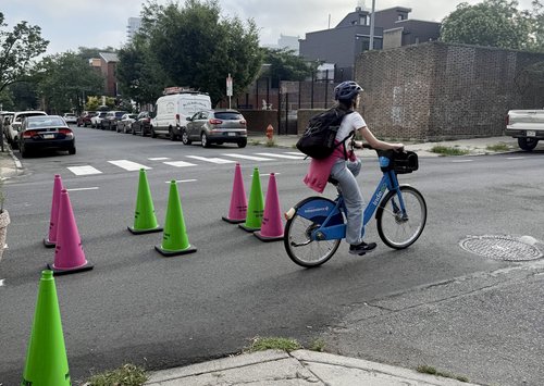 Woman rides Indego bike through PBA cones at LeCount St